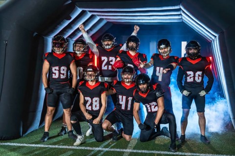 American football team players standing ready to enter the stadium through a tunnel, wearing