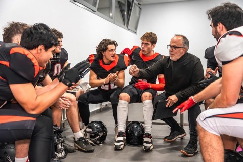 American football coach briefing players in a locker room, outlining strategy and motivating the