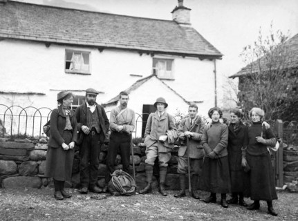 Men and women in mountaineering mountain climbing group standing in fron of cottage, c 1900-1920
