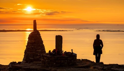 Silhouette of a woman watching the sunset next to cairns, Rørsethornet stone staircase, with 3292