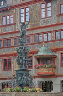 Neptune fountain with sculpture of Neptune Roman god of the sea with trident on the house facade