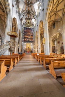 Gothic church with detailed construction, wooden benches and large painted banner above the altar
