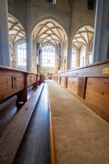 Bright church interior with long wooden benches, Gothic windows and vaulted ceiling, St Nicholas