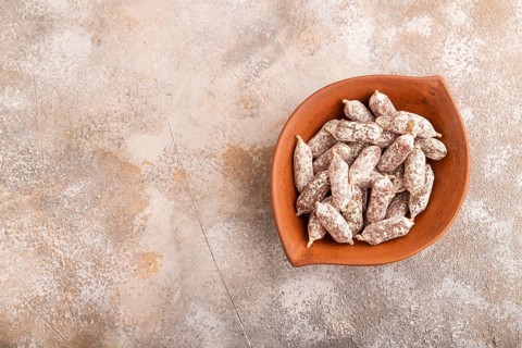 Small smoked Chicken sausages in clay bowl on brown concrete background. top view, copy space