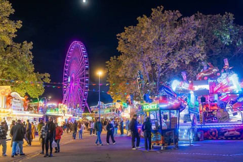 Lively night shot with illuminated Ferris wheel and colourful festival stands, Cannstatter Wasen