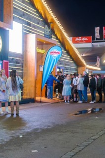 People standing in front of an illuminated marquee at night while waiting for admission,