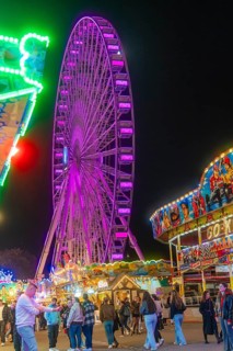 Ferris wheel shining through the night and colourful stalls attract visitors, Cannstatter Wasen