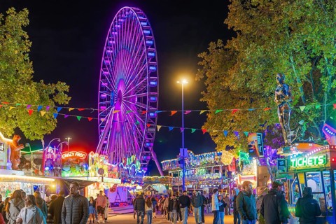 Lively scenery with colourful lights and a large Ferris wheel, Cannstatter Wasen folk festival,