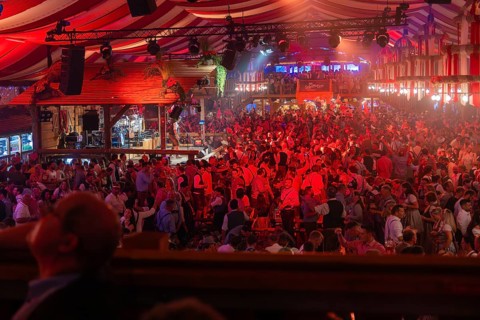 A well-attended marquee with red lights and a cheerful party atmosphere, Cannstatter Wasen folk
