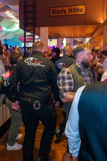 Security guards in a busy marquee during a party, Cannstatter Wasen folk festival, Stuttgart,
