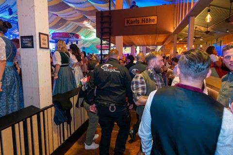 Lively beer tent with security guards and festive atmosphere, Cannstatter Wasen folk festival,