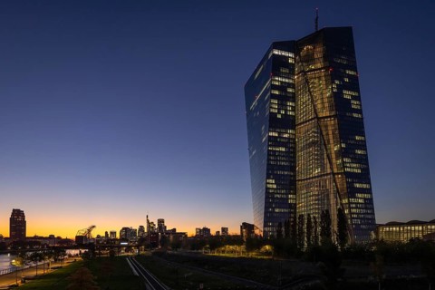The lights of the European Central Bank (ECB) and the Frankfurt banking skyline glow in the