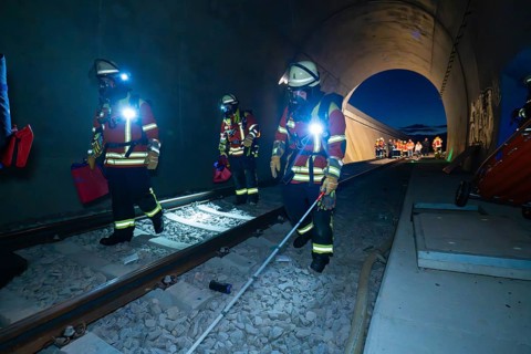 Firefighters walk along tracks in a tunnel at night, firefighting exercise in the new tunnel of the