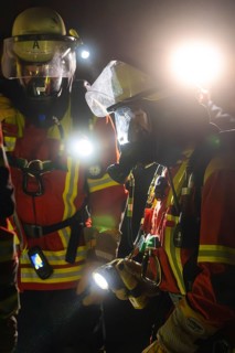 Firefighters in protective suits at night with torches in action, firefighting exercise in the new