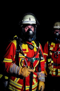 Firefighter with breathing apparatus in the dark, concentrated and ready for action, firefighting