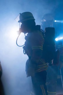 Firefighters with breathing masks in a foggy environment with bright light, firefighting exercise