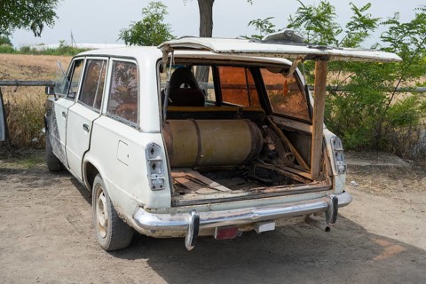 An old estate car with an open tailgate shows a gas bottle lying inside, car has gas tank