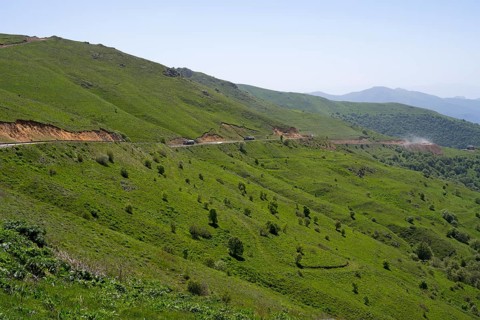 Road runs along the green hills in a landscape with mountains, at the highest pass in Armenia,