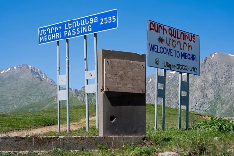 Signs on a roadside indicating the border to a place in a mountainous region, at the highest pass