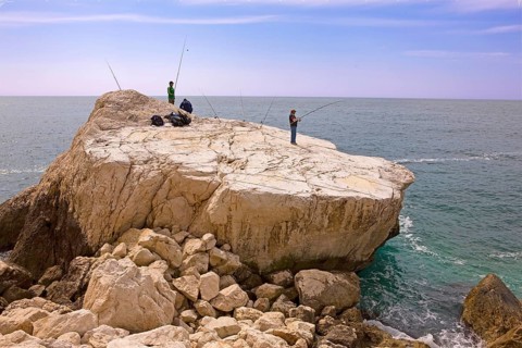 Angler, fishing, rocky plate, south at the rock Penon de Ifach landmark, Mediterranean Sea, bay,