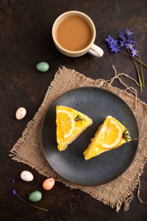 Lemon cake on black concrete background and linen textile, cup of coffee, top view, flat lay, close