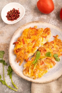 Baked chicken meat with cheese and tomatoes on brown concrete background and linen textile. side