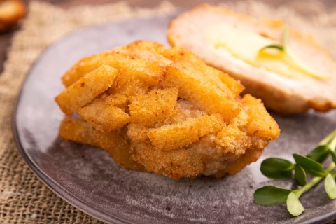 Chicken Schnitzel on gray plate with microgreen on brown wooden background and linen textile. side
