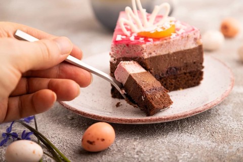 Chocolate cake with hand on brown concrete background, cup of coffee, side view, close up,