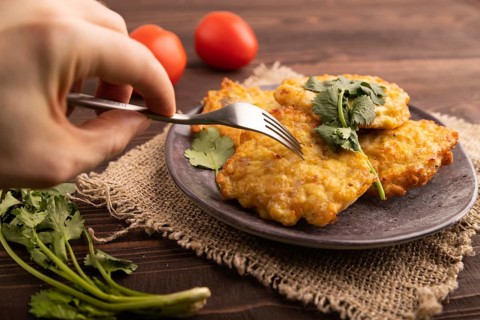 Fried crispy Chicken pancakes with hand on brown wooden background and linen textile. side view,