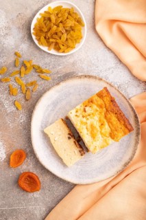 ?ottage cheese ?asserole, Curd cake, with dried apricots and raisins on brown concrete background