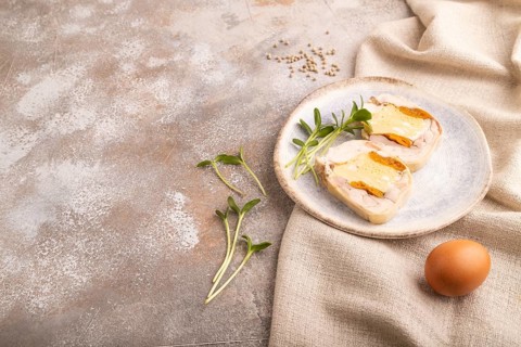Chicken, egg and dried apricot meatloaf, microgreen on brown concrete background and linen textile.
