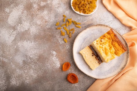 ?ottage cheese ?asserole, Curd cake, with dried apricots and raisins on brown concrete background