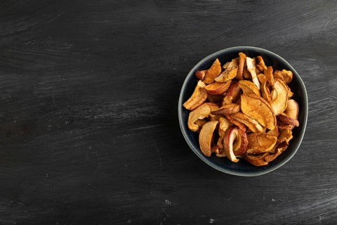 Dried Apples in ceramic bowl on black wooden background. Top view, copy space, flat lay. healthy
