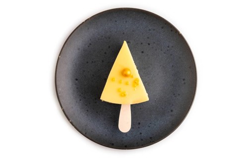 Yellow Cake pop with sprinkles on blue ceramic plate isolated on white background, top view, flat