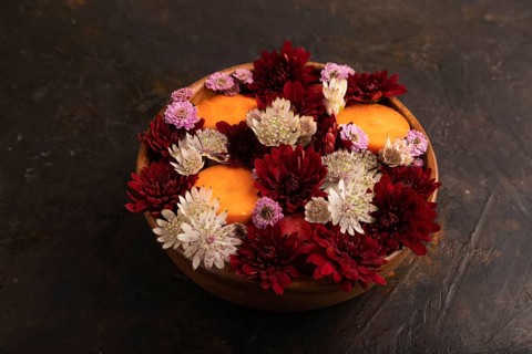 Wooden bowl with carrot slices and red Chrysanthemum flowers, Astrantia flowers, flower salad on