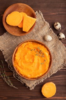Sweet potato porridge in wooden bowl on wooden background and linen textile. Diet, healthy eating