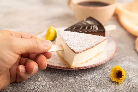 Chocolate and Vanilla Cake pops Marshmallow with hand with cup of coffee on brown concrete