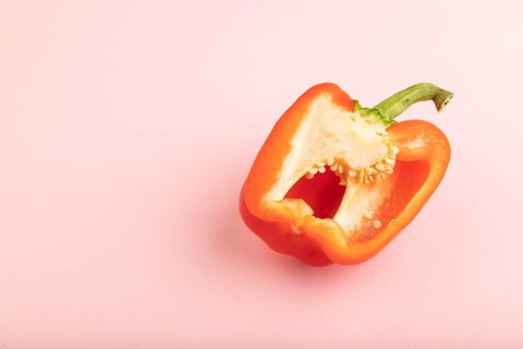 Red Cutted pepper on pink pastel background. Side view, copy space. Tropical, healthy food,