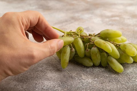 Green grapes on gray concrete background. Side view, close up. healthy food, minimalism