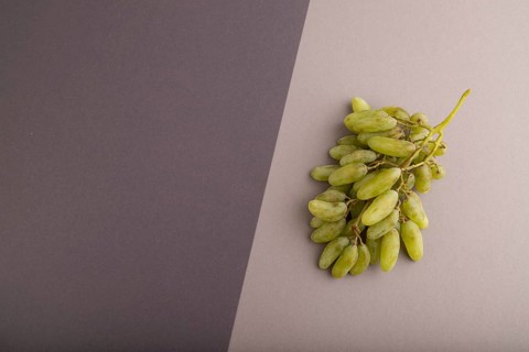 Green grapes on gray and black paper pastel background. Top view, flat lay, copy space. healthy