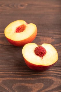 Peach Cut in half on brown wooden background. Side view, flat lay, close up. healthy food,