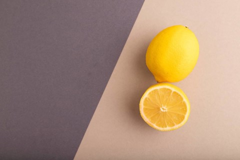 Yellow Lemon Cut in half on beige and gray pastel paper background. Top view, flat lay, copy space.