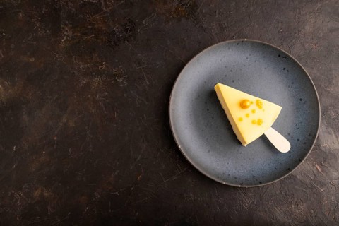 Yellow Cake pop with sprinkles on blue ceramic plate on black concrete background, top view, flat