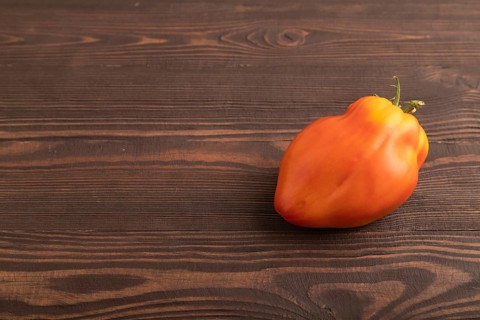 Red Heart Shape tomato on brown wooden background. Side view, copy space. healthy food, vegetable,