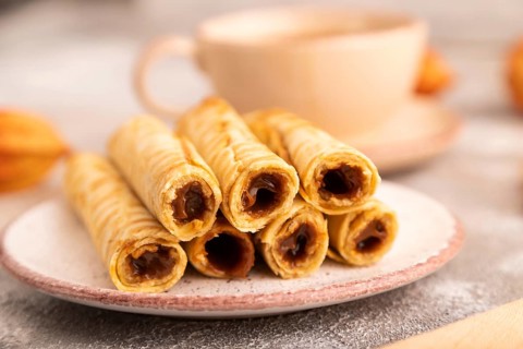 Waffles with caramel on brown concrete background and orange linen textile, cup of coffee, side