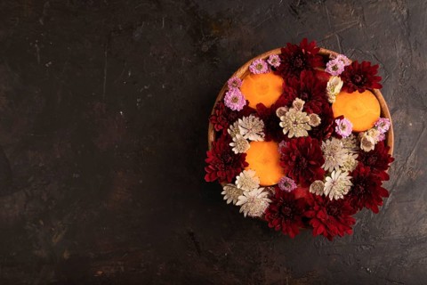 Wooden bowl with carrot slices and red Chrysanthemum flowers, Astrantia flowers, flower salad on