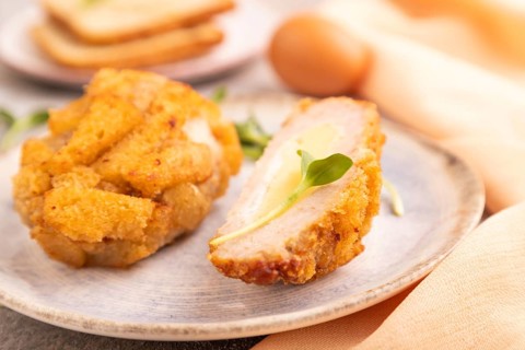 Chicken Schnitzel on blue plate with microgreen on brown concrete background and orange linen