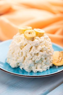 White ?ottage cheese, Curd, with Banana on blue wooden background and orange textile, side view,