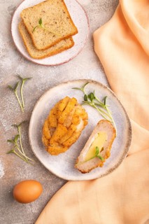 Chicken Schnitzel on blue plate with microgreen on brown concrete background and orange linen
