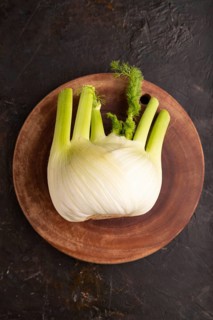 Fresh Fennel bulb on wooden cutting board on black concrete background, top view, flat lay, copy